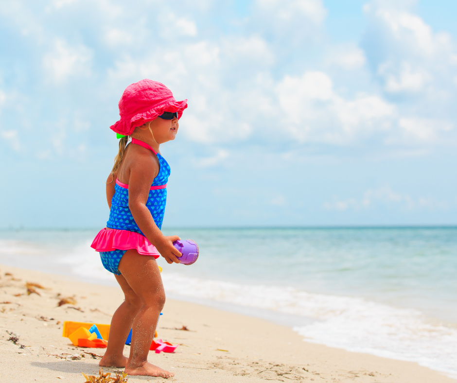 Toddler on the beach in a blue and pink swimsuit
