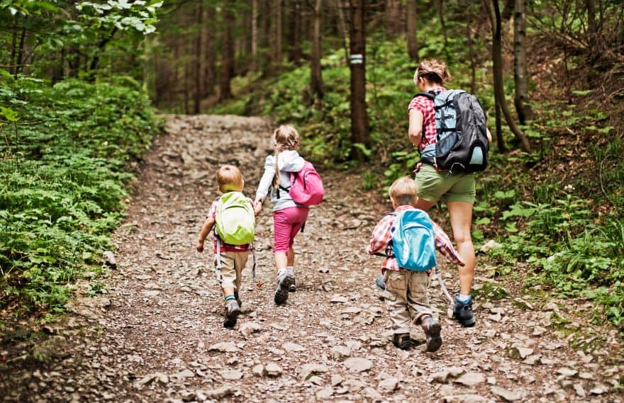 A man going on a hike with three kids while carrying bags